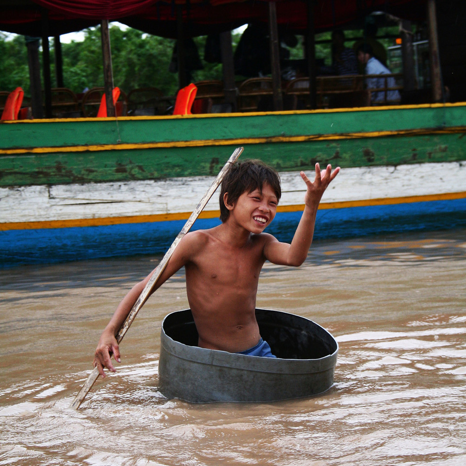 A man in an inner tube beside colourful boats